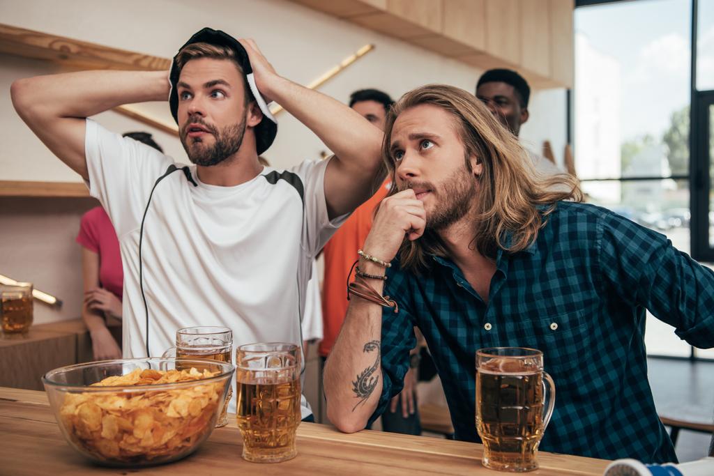 kızgın genç adam futbol topu şapkalı elele kafa ve onun arkadaşı izle futbol maçın sırasında bar  - Fotoğraf, Görsel