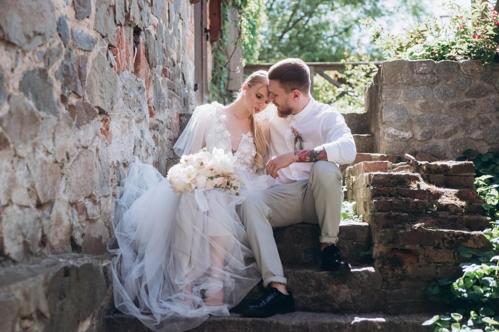 bride and groom sitting on stairs at old town - Photo, Image