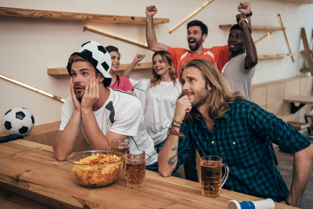 nadšený skupina multikulturní přátel slavit a sledovat fotbalový zápas na bar s pivem a čipy  - Fotografie, Obrázek