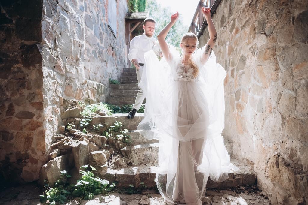 Nevěsta a ženich na schodech ze starobylé budově v historickém centru města - Fotografie, Obrázek
