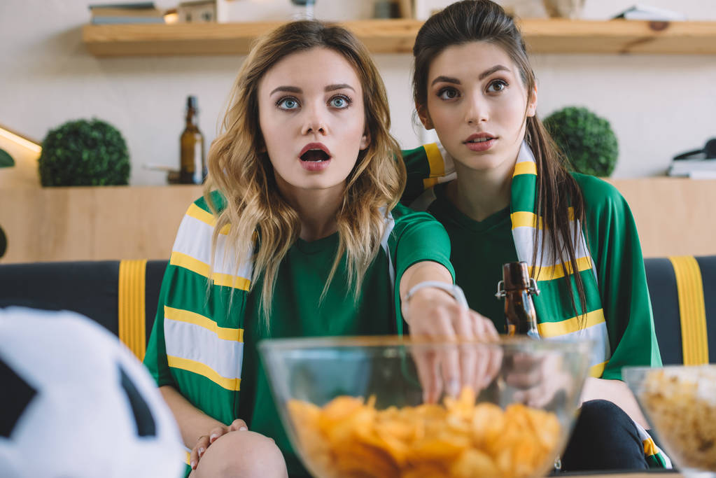 шоковані фанати жіночого футболу в зелених футболках і шарфі, жестикулюючи руками під час спостереження за футбольним матчем вдома
 - Фото, зображення