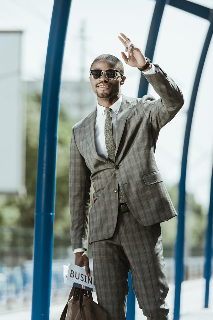Giovane uomo d'affari afroamericano che saluta qualcuno alla stazione ferroviaria
 - Foto, immagini