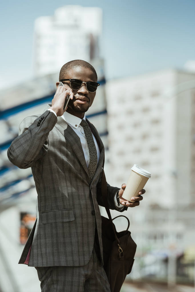 Elegante uomo d'affari fiducioso parlando su smartphone e tenendo tazza di caffè in attesa di treno
 - Foto, immagini