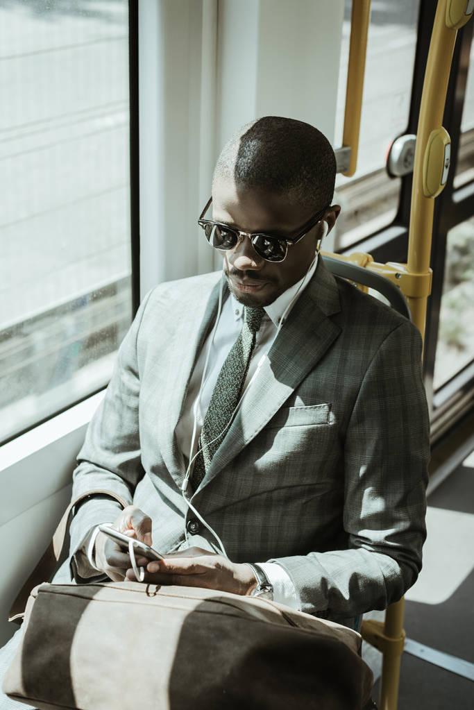 Joven empresario afroamericano escuchando música mientras toma tren
 - Foto, Imagen