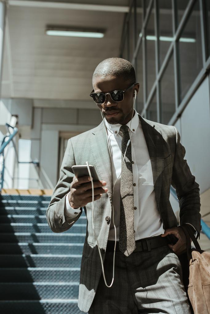 Κομψό αυτοπεποίθηση επιχειρηματίας χρησιμοποιώντας smartphone, ενώ το περπάτημα σε σκάλες - Φωτογραφία, εικόνα