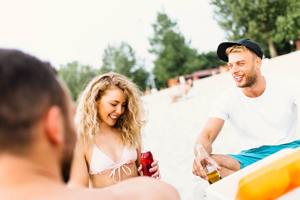 Grupo de jóvenes atractivos disfrutando en la playa, bebiendo y brindando. - Foto, imagen