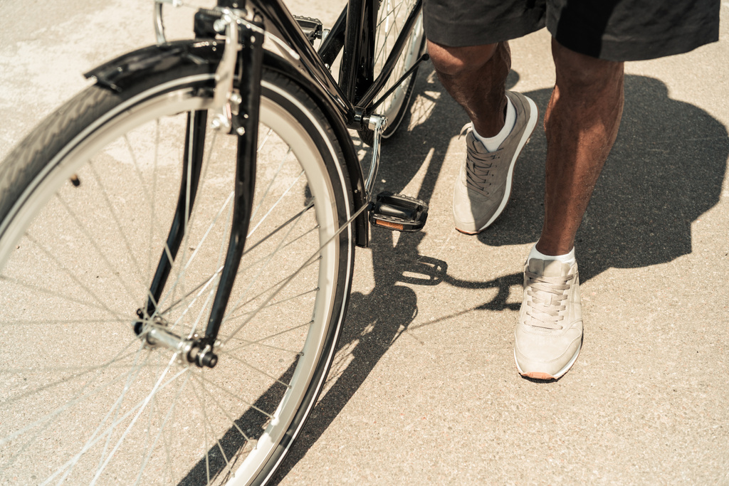 Обрізаний подання афро-американських чоловік, що стоїть на своєму велосипеді - Фото, зображення