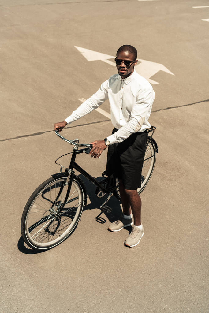 Красивий молодий афроамериканець людиною, що стоїть на своєму велосипеді на вулиці - Фото, зображення