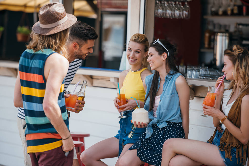 boldog, fiatal férfiak és nők, beszélgetni, és ivott a koktélok a strand bárban - Fotó, kép