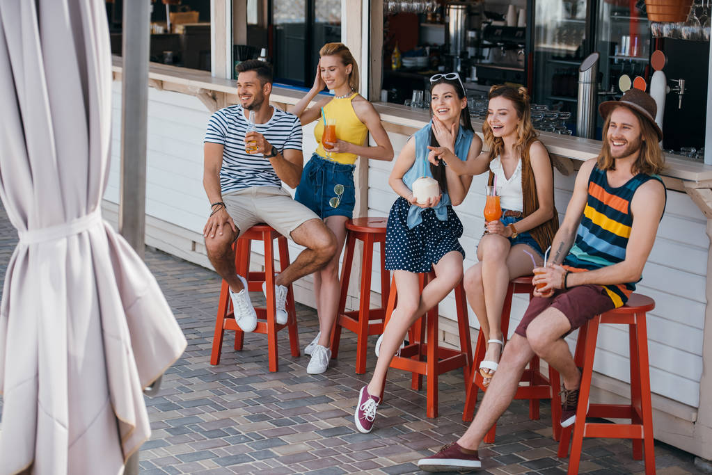 vista de ángulo alto de amigos jóvenes felices bebiendo cócteles en el bar de la playa
 - Foto, imagen