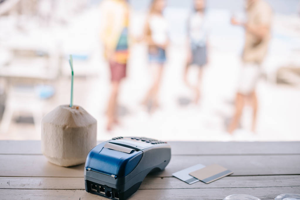 close-up view of summer cocktail with drinking straw and payment terminal with credit cards on bar counter at beach bar - Photo, Image