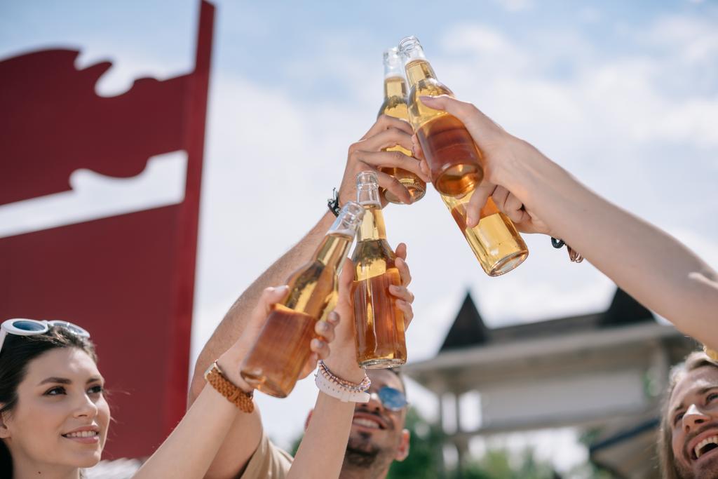 giovani sorridenti clinking bottiglie di birra al giorno d'estate
  - Foto, immagini