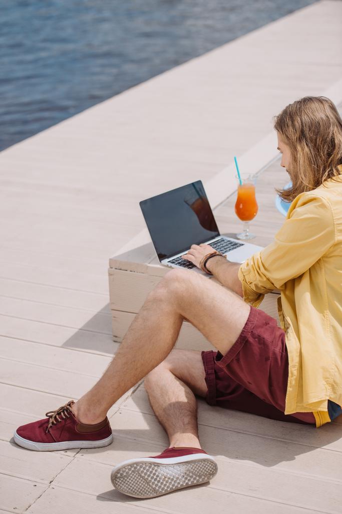 visão de alto ângulo do jovem usando laptop com tela em branco na praia
 - Foto, Imagem