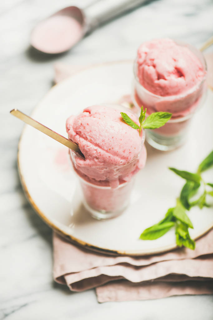 Καλοκαιρινό γλυκάκι υγιούς χαμηλής θερμίδας. Φράουλα γιαούρτι σπιτικό παγωτό με φρέσκο δυόσμο σε ποτήρια στο πιάτο πάνω φόντο γκρι μαρμάρινο τραπέζι. - Φωτογραφία, εικόνα