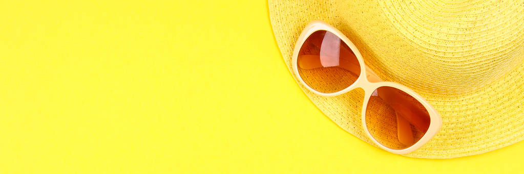 Kapelusz, okulary przeciwsłoneczne na pastelowym żółtym tle - Zdjęcie, obraz