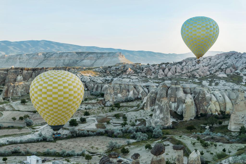 front view of two hot air balloons flying over stone formations in valley of Cappadocia, Turkey - Photo, Image