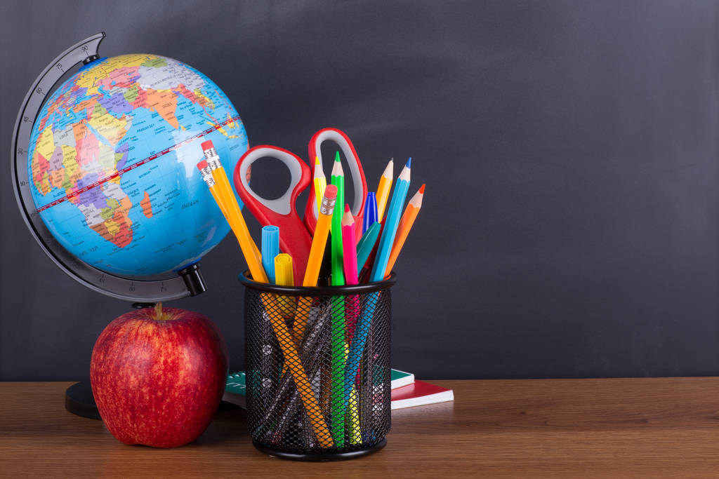 School accessories and an apple on a desktop with a chalkboard background for copy space - Photo, Image