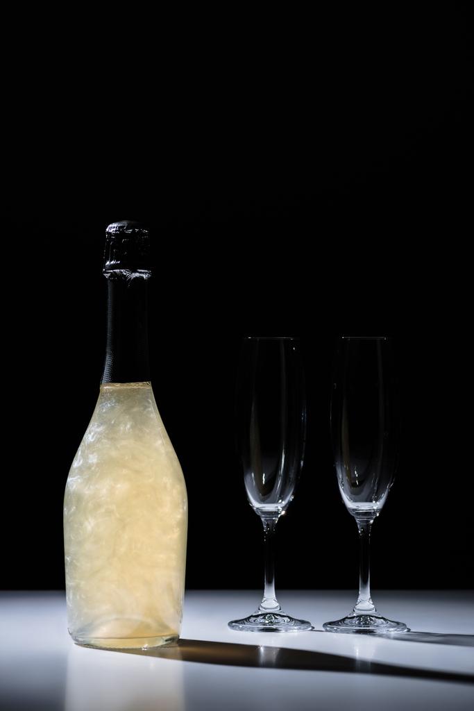 vista de perto de garrafa de champanhe e copos vazios no fundo preto
 - Foto, Imagem