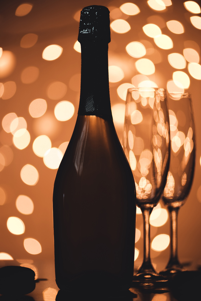 close up view of bottle of champagne and empty glasses on tabletop in bokeh style - Photo, Image