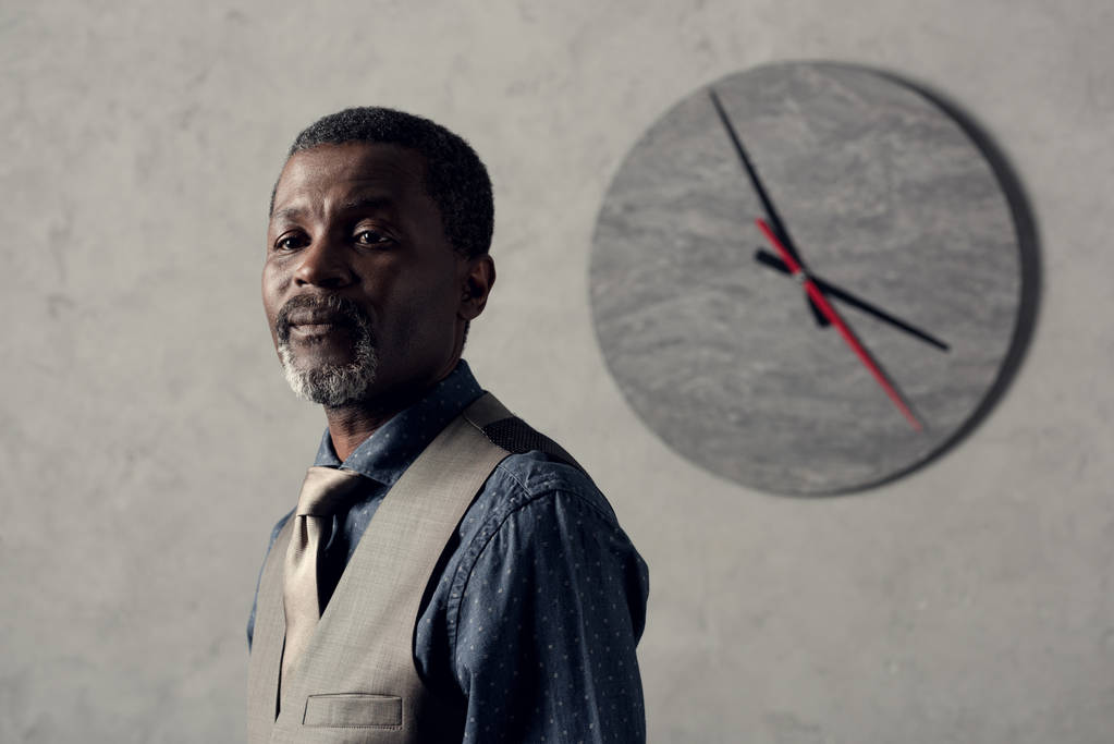 portrait de l'homme afro-américain élégant en gilet avec horloge sur le mur
 - Photo, image