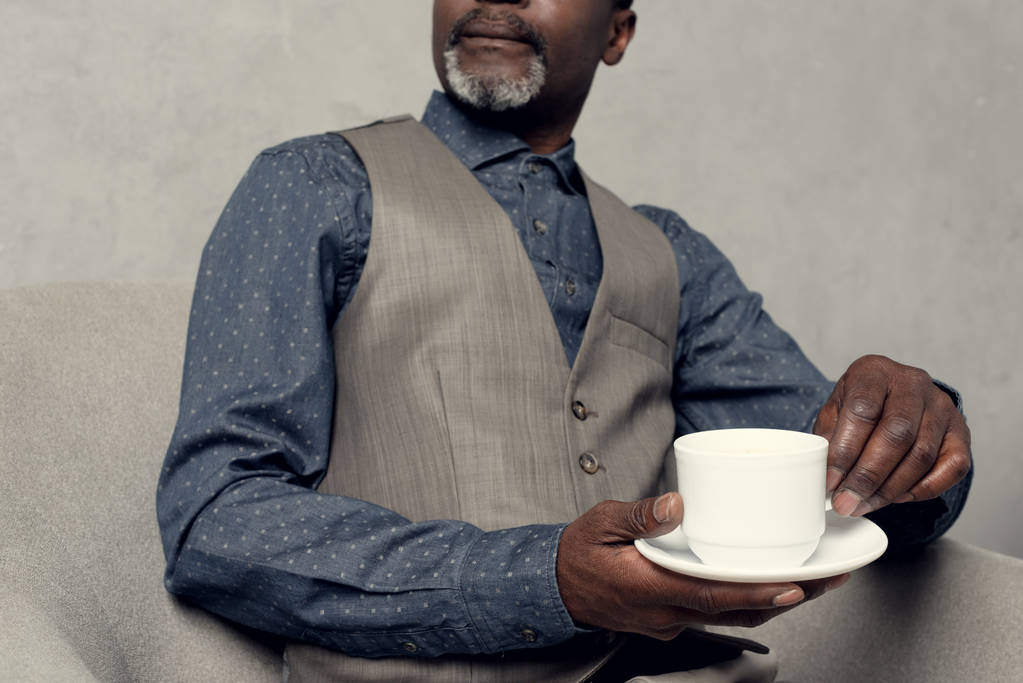 vista cortada de homem americano africano elegante em colete segurando xícara de café
 - Foto, Imagem