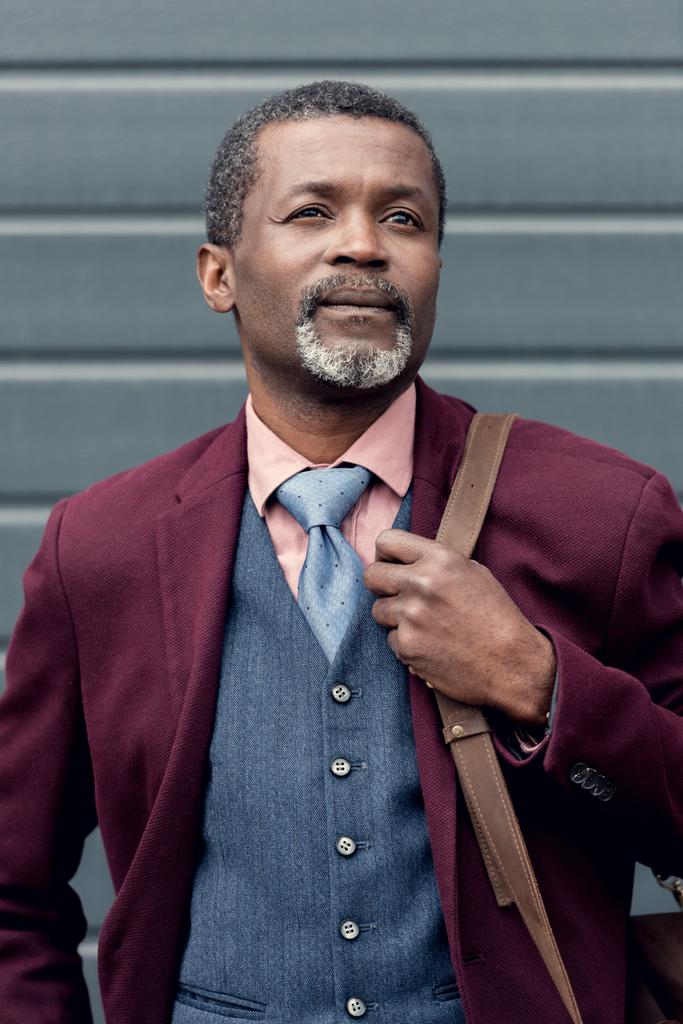 élégant homme afro-américain réfléchi en veste bordeaux avec sac
 - Photo, image