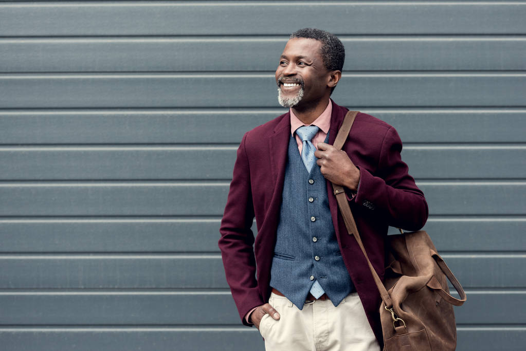 счастливый стильный африканский американец в бордовом пиджаке с кожаной сумкой
 - Фото, изображение