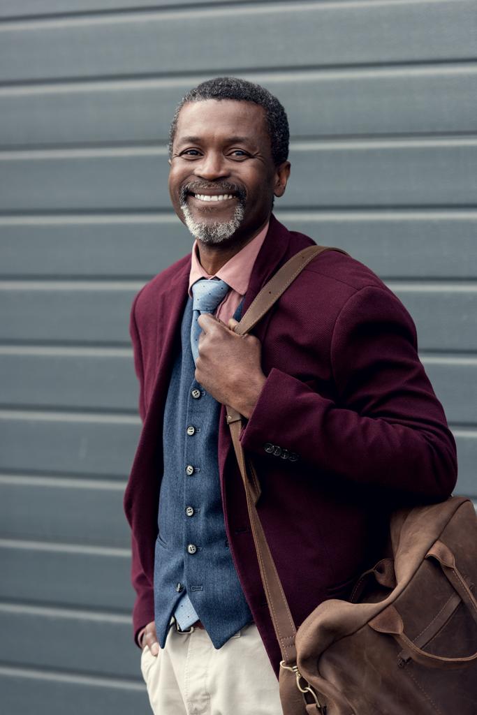 glimlachend volwassen Afrikaanse Amerikaanse man met lederen tas - Foto, afbeelding