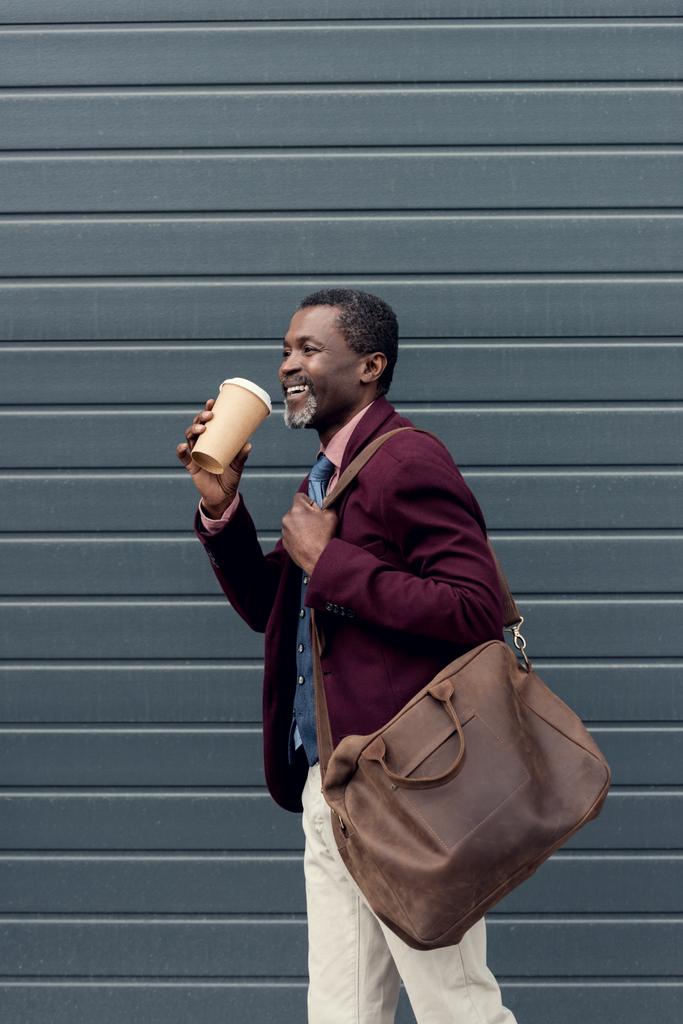 μοντέρνα αφρικανική αμερικανική άνθρωπος με δερμάτινη τσάντα και μίας χρήσης φλιτζάνι καφέ   - Φωτογραφία, εικόνα