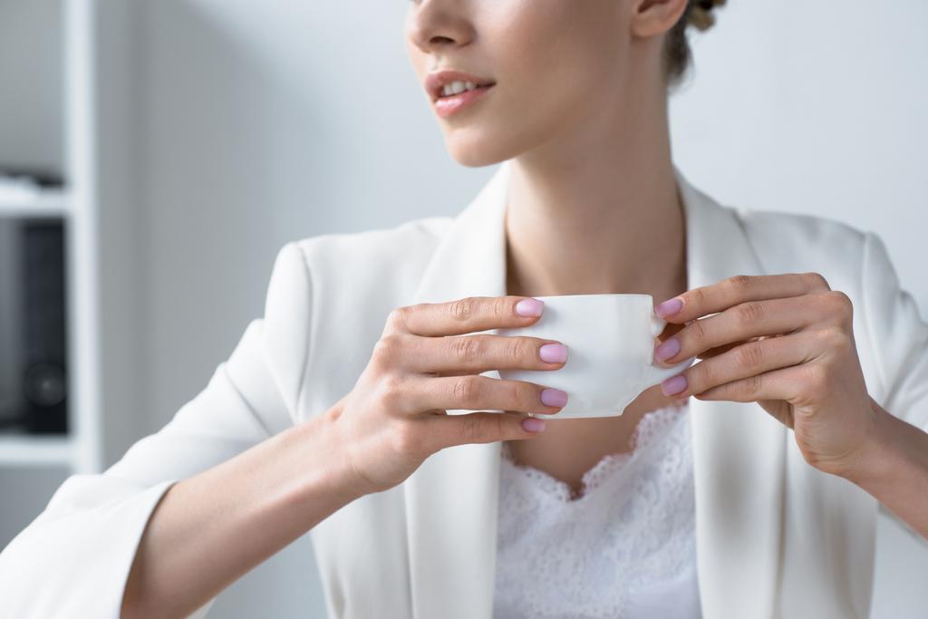 colpo ritagliato di giovane donna d'affari che beve caffè in ufficio
 - Foto, immagini