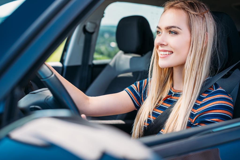 primo piano colpo di sorridente giovane donna guida auto
  - Foto, immagini