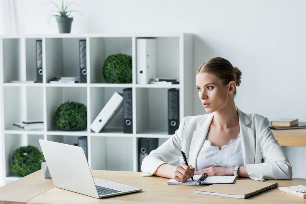 привлекательная молодая деловая женщина делает заметки во время работы в офисе
 - Фото, изображение