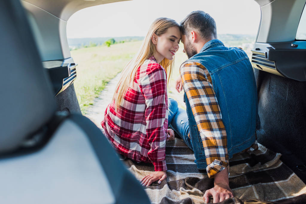 jeune couple assis sur le coffre de la voiture dans le domaine rural
  - Photo, image