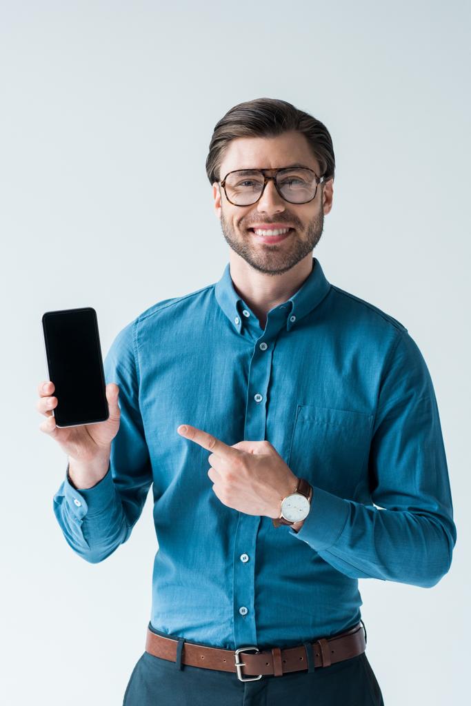 happy young man holding smartphone and pointing at blank screen isolated on white - Photo, Image