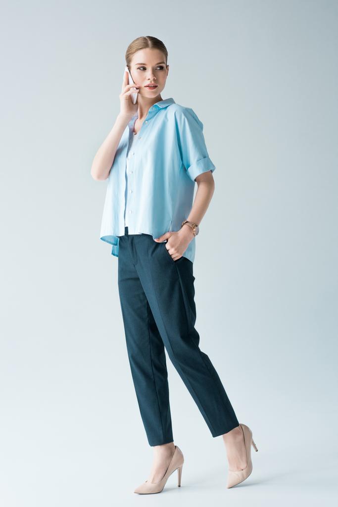 ελκυστική νεαρή γυναίκα στο μπλε πουκάμισο μιλάμε από το τηλέφωνο σε γκρι - Φωτογραφία, εικόνα