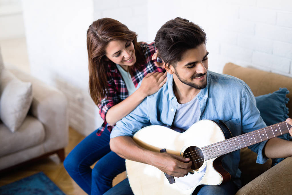 jonge knappe man gitaarspelen voor zijn vriendin - Foto, afbeelding