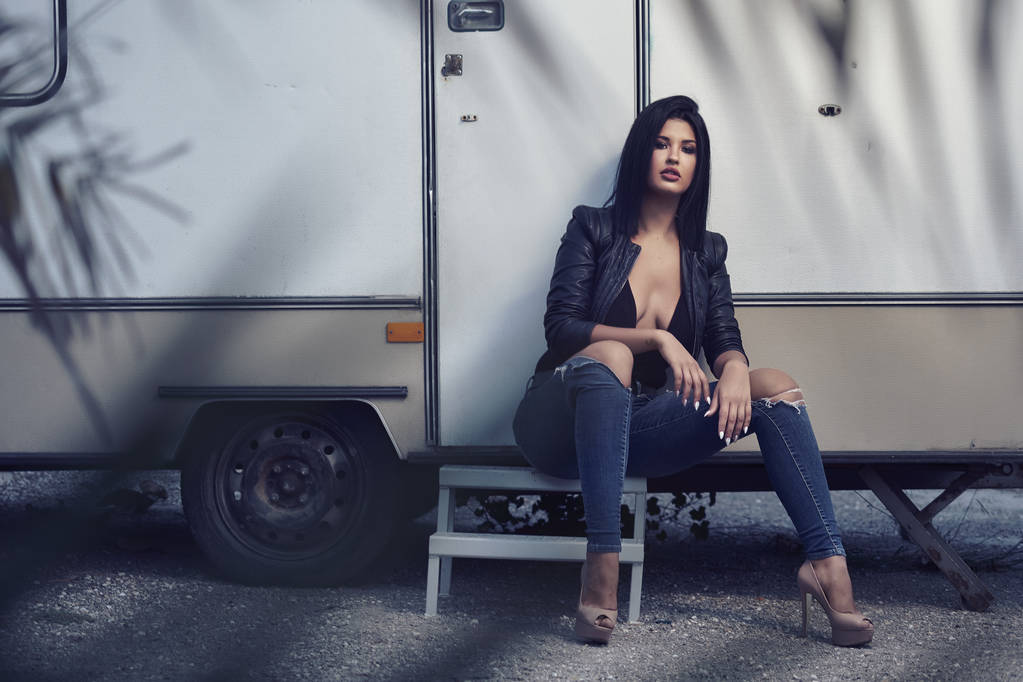 Sexy mujer morena sentada cerca de caravana remolque
 - Foto, Imagen