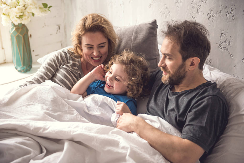 Beata famiglia sta iniziando il nuovo giorno insieme in dormitorio luminoso
 - Foto, immagini