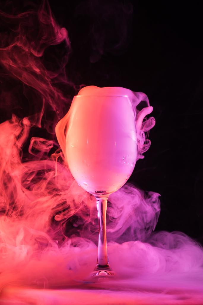κρασί ποτήρι γεμάτο καπνό ροζ σε σκούρο φόντο - Φωτογραφία, εικόνα