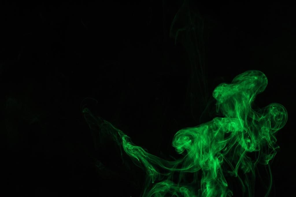 kreativer schwarzer Hintergrund mit grünem Rauch  - Foto, Bild