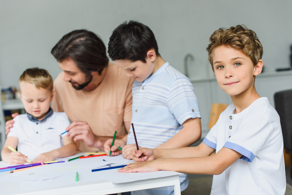 селективное внимание отца помогает сыновьям рисовать картинки с цветными карандашами дома
 - Фото, изображение
