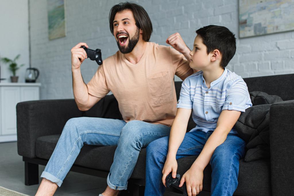 père émotionnel et fils jouant ensemble à des jeux vidéo à la maison
 - Photo, image