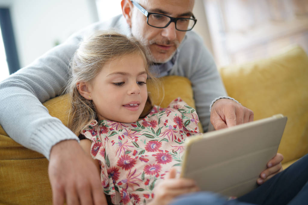 Apa és lánya kapcsolódik tabletta, ül a kanapén - Fotó, kép