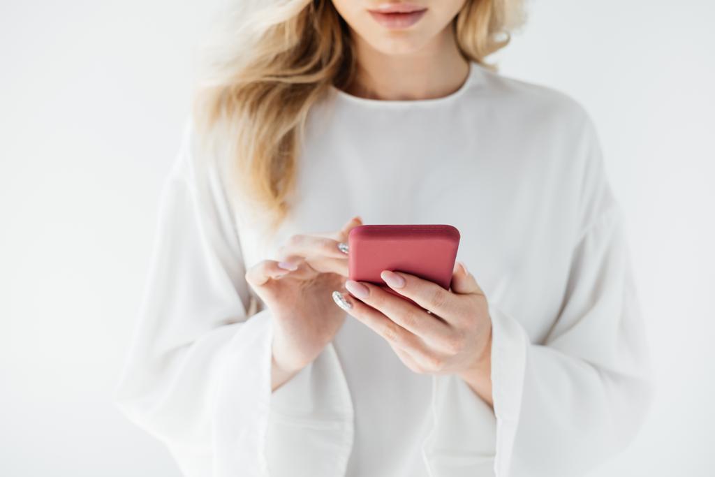 Schnappschuss einer Frau in weißer Kleidung mit Smartphone vor grauem Hintergrund - Foto, Bild