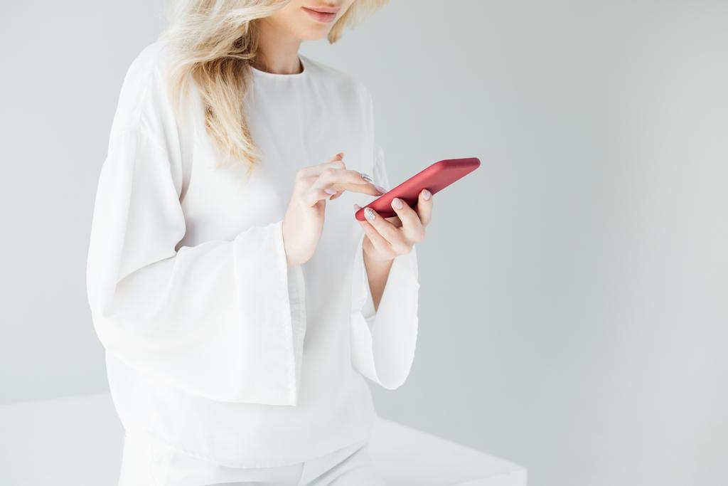 cropped shot of woman in white clothing using smartphone on grey backdrop - Photo, Image