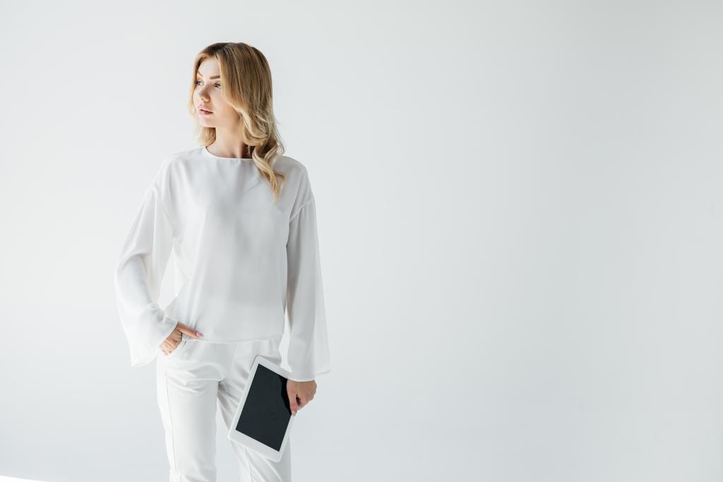 πορτρέτο της νεαρής γυναίκας σκεπτικός σε λευκά ρούχα με tablet που απομονώνονται σε γκρι - Φωτογραφία, εικόνα