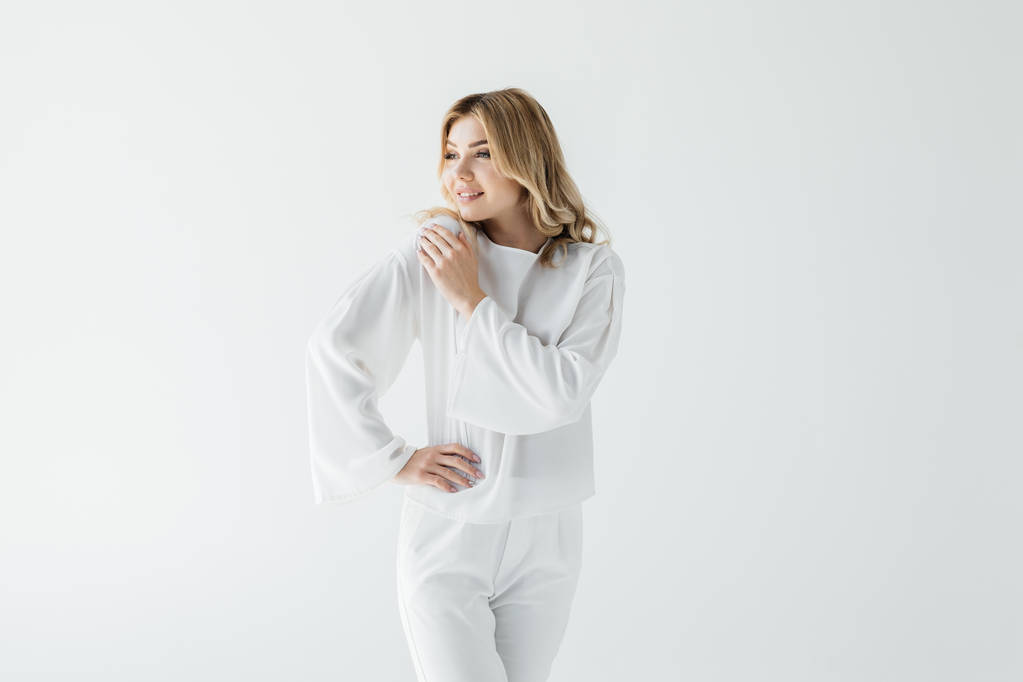 Portret van mooie lachende vrouw in witte kleding op zoek weg op wit wordt geïsoleerd - Foto, afbeelding