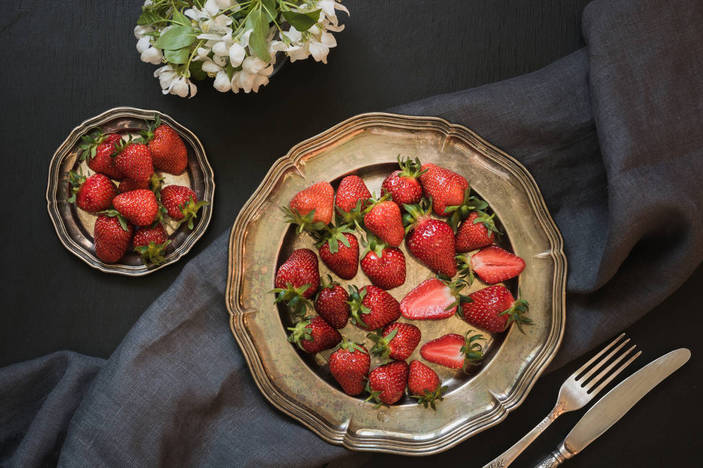 Fresa orgánica fresca en plato vintage sobre mesa negra. Primavera. Vista superior
. - Foto, Imagen