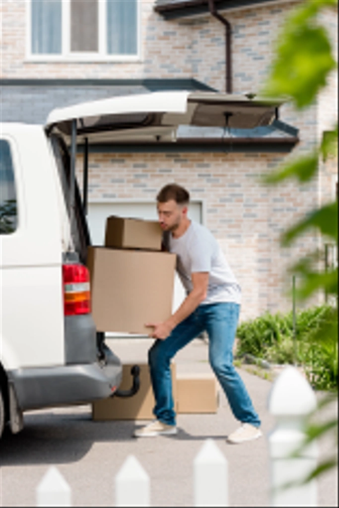 enfocado joven hombre moviendo cajas de coche en nueva casa
  - Foto, Imagen