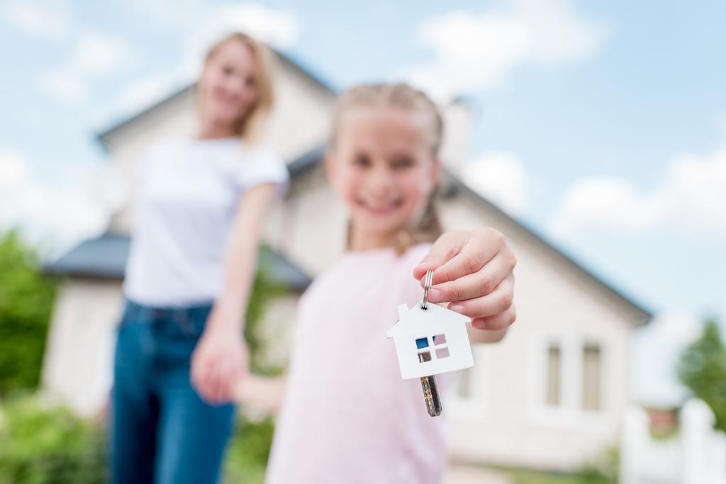 Zamknij widok klucza z cacko w ręce dzieci trzymając dłoń matki przed Nowy Domek  - Zdjęcie, obraz